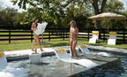 Guests positioning a white chaise riser and loungers on a pool sun shelf.