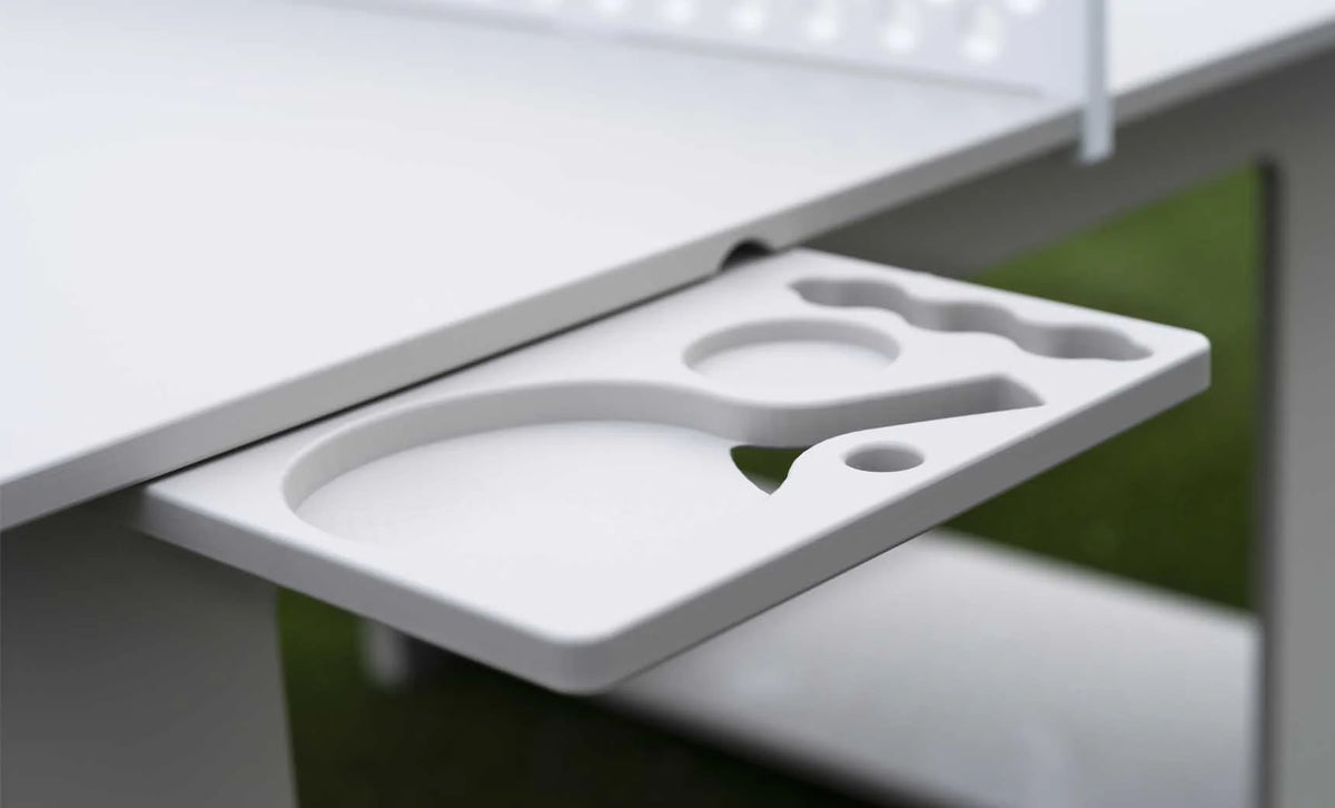 Pull-out accessory tray beneath the all-weather table tennis set with molded storage for paddles, balls and drinks