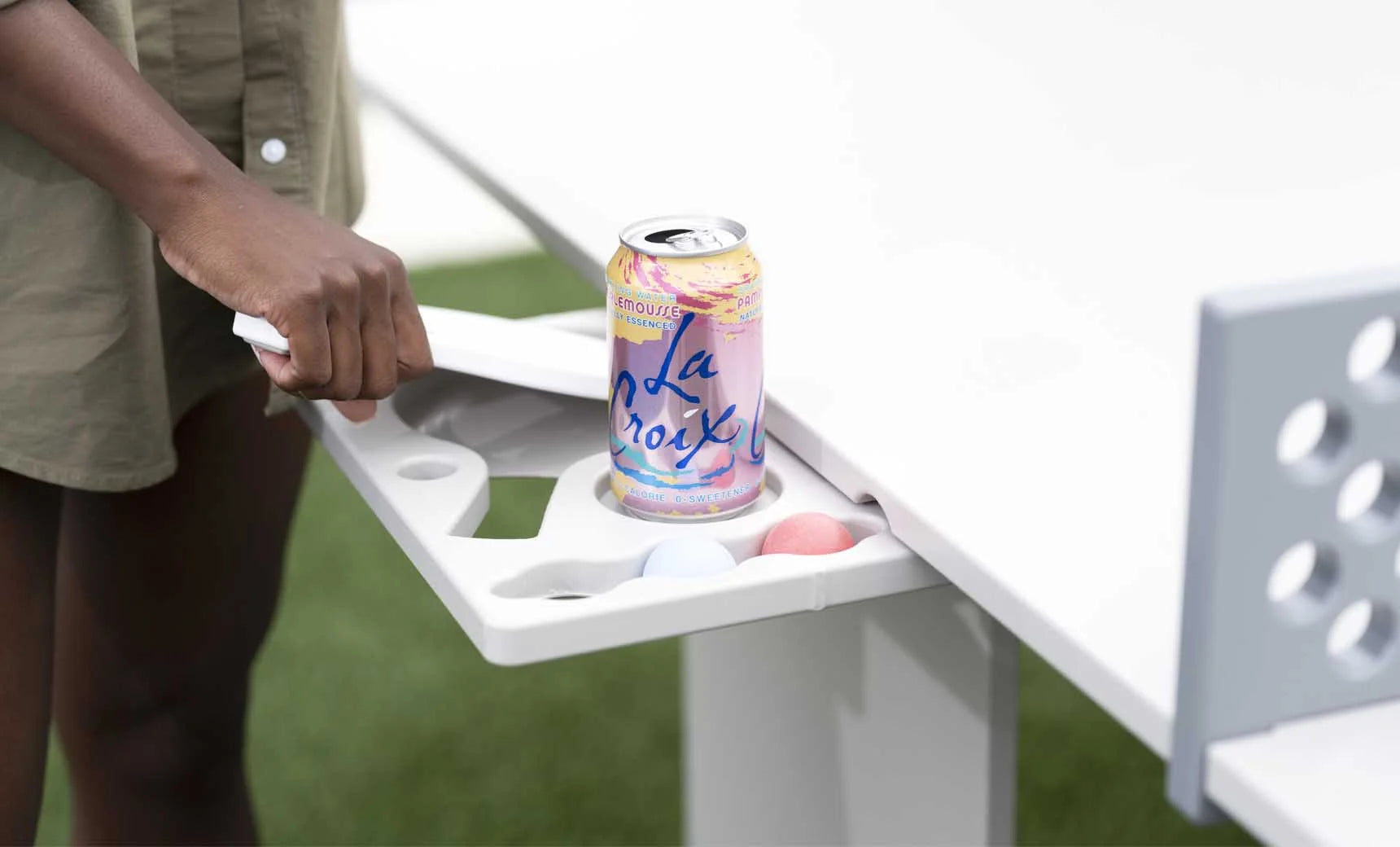 Pull-out accessory tray on the all-weather table tennis set holding a drink can, balls and a paddle