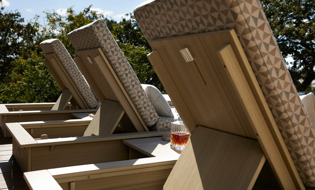 Rear detail of Ledge Lounger Echo chaise backrests, showing woodgrain-look frames, support positions and patterned cushions.