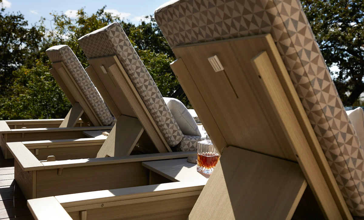 Rear detail of Ledge Lounger Echo chaise backrests, showing woodgrain-look frames, support positions and patterned cushions.