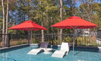 Two red 9-foot Premier Umbrellas shading in-pool chaise lounges on a residential pool ledge