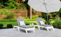Two white adjustable poolside chaise lounges with gray cushions beneath a patio umbrella.
