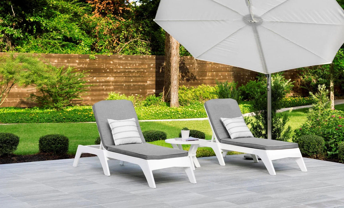 Two white adjustable poolside chaise lounges with gray cushions beneath a patio umbrella.