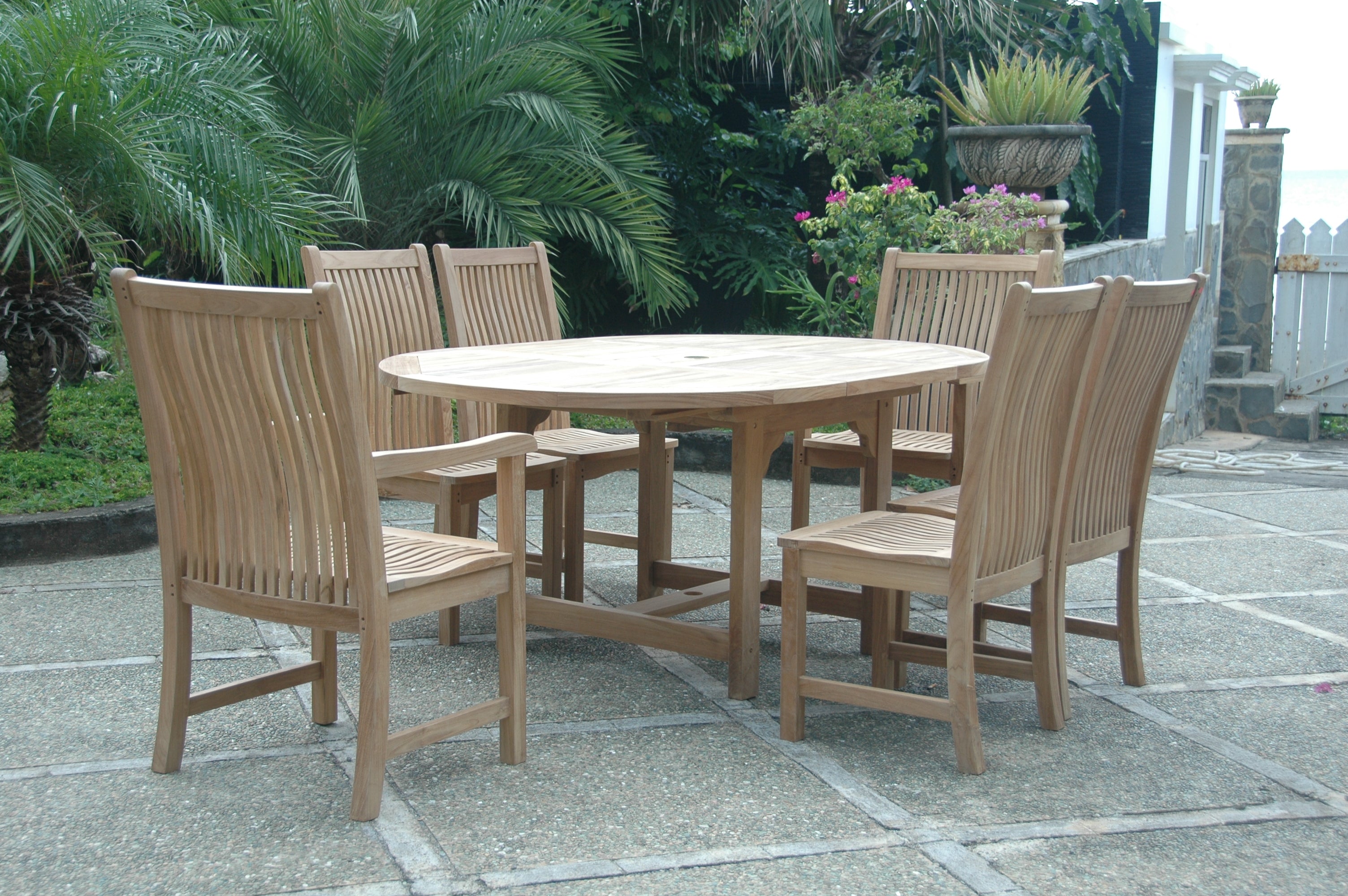 Bahama Chicago dining set on a garden patio with the table in its closed round position and six teak chairs around it