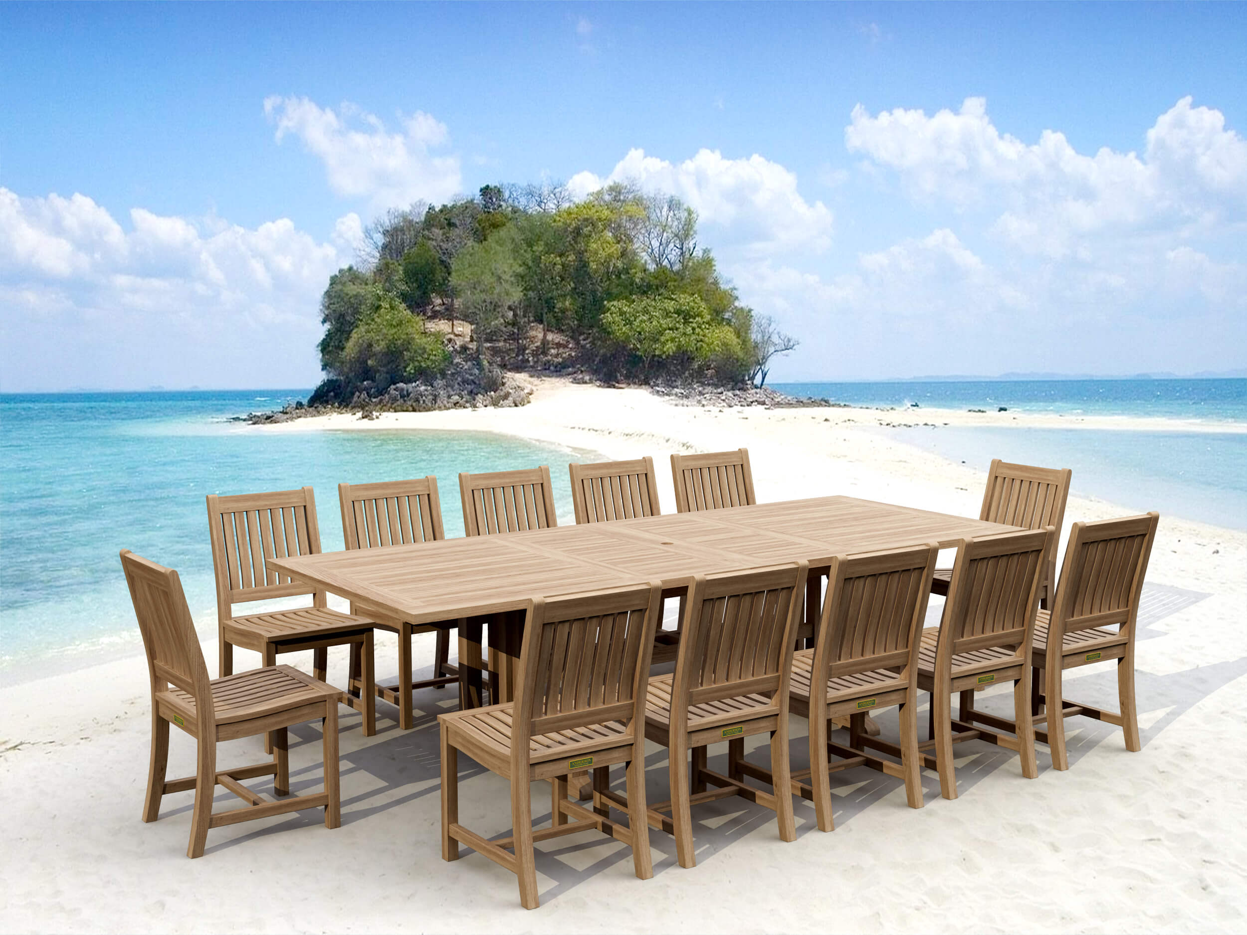 Sahara Rialto rectangular teak extension dining table with twelve armless slat-back teak chairs set up on white sand beside turquoise water