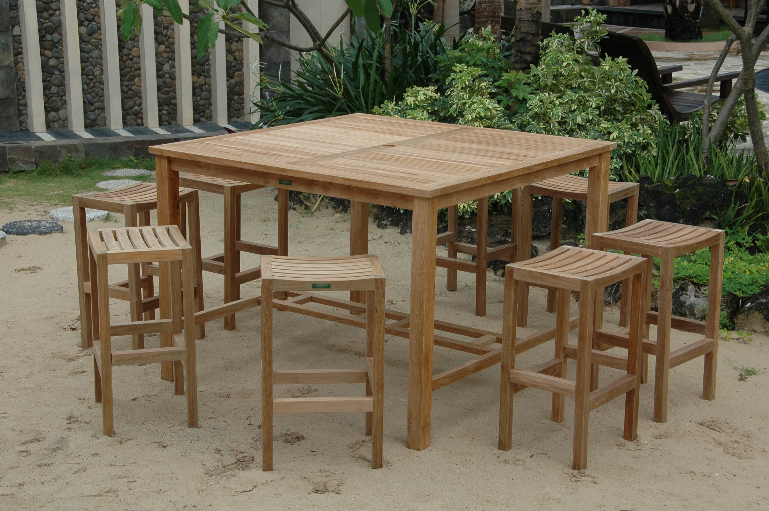 Windsor square teak bar table with eight Montego backless bar chairs in an outdoor garden setting