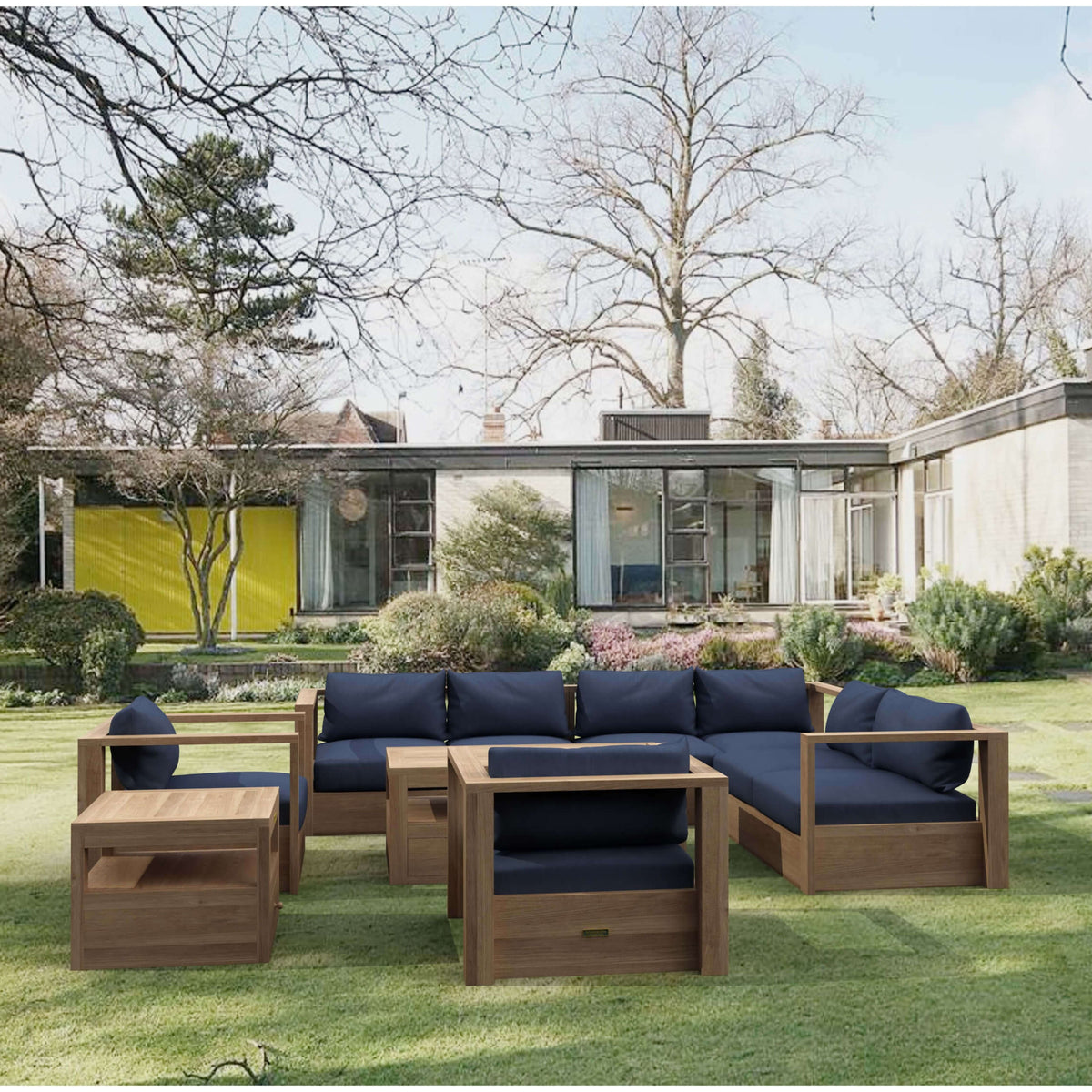 Copacabana modular teak deep seating set with navy cushions arranged on a landscaped lawn