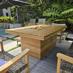 Close poolside view of the Louvre slatted teak tabletop, lit burner, glass wind guard and base controls.