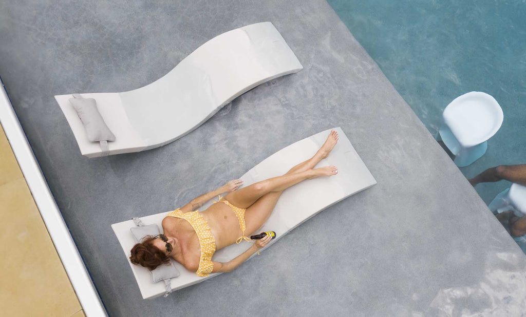 Overhead view of a person reclining on a White Signature Chaise beside a second chaise and side table