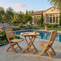 Bahama Andrew round teak bistro table and two folding chairs beside a garden pool