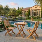Bahama Andrew round teak bistro table and two folding chairs beside a garden pool