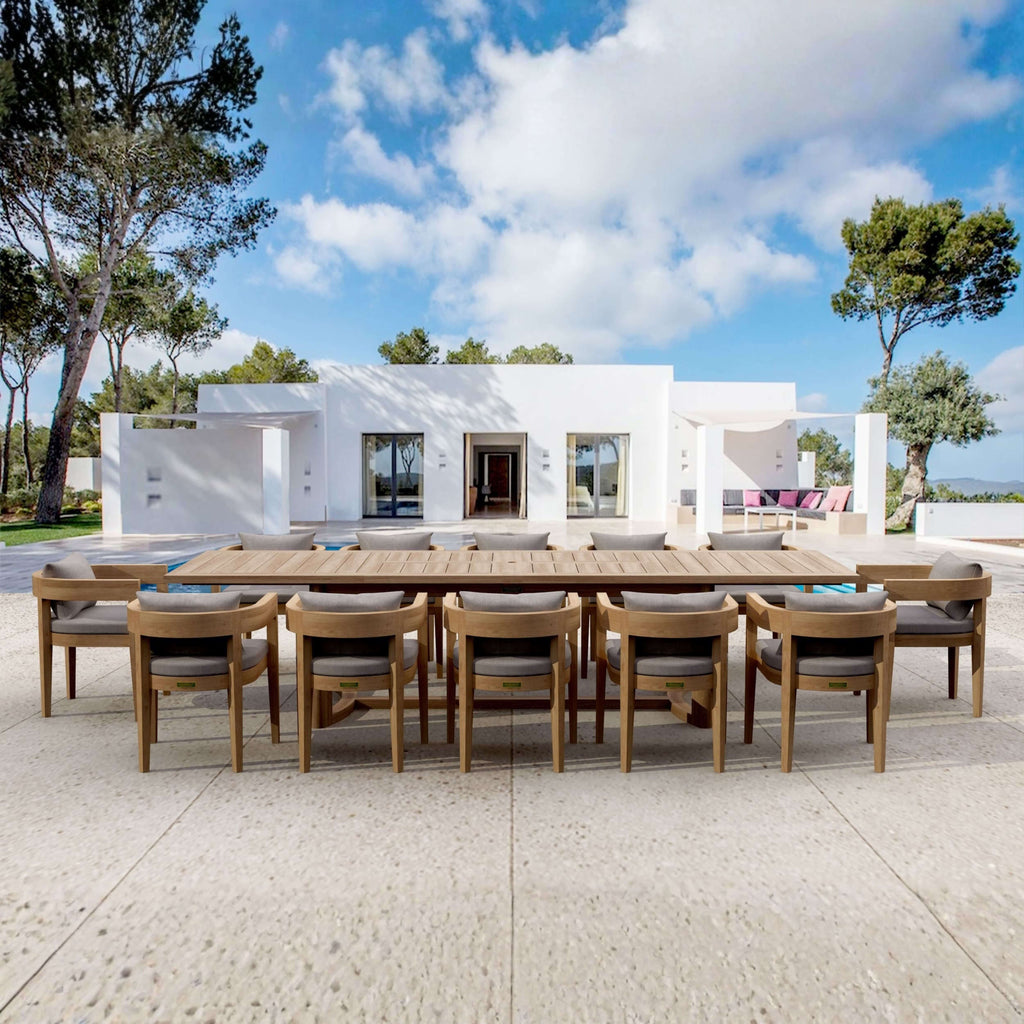 Coronado teak dining set for twelve with cushioned armchairs on a poolside terrace.