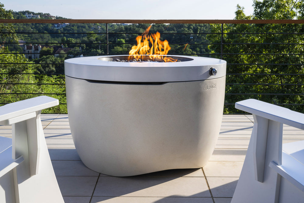 Ledge Halo firepit with a visible flame beside white patio seating and greenery