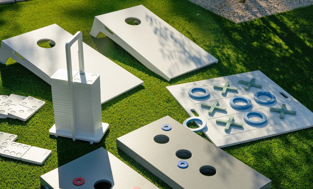 Two White Cornhole Toss boards in a backyard game setting; other games and furnishings shown are sold separately
