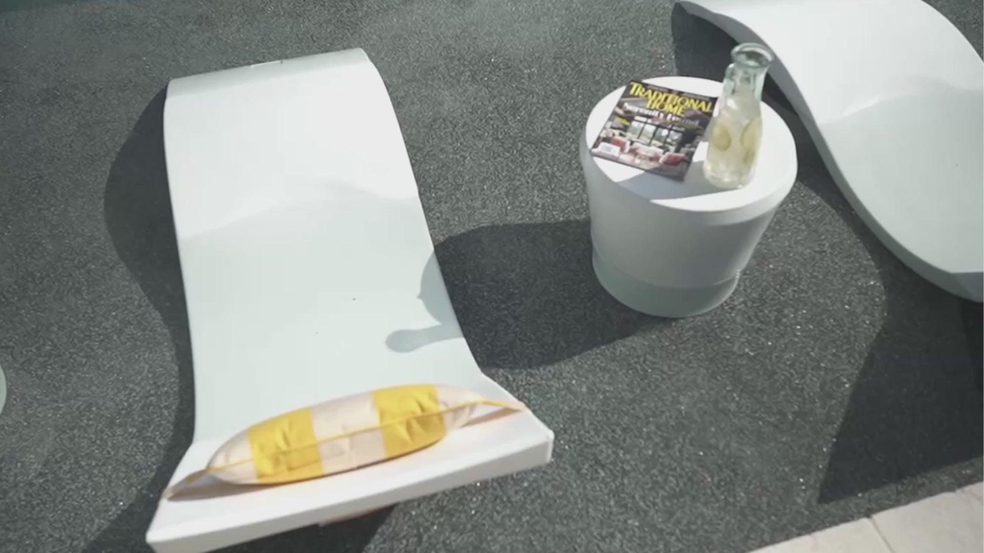 Video of a White Signature Chaise with a pillow and side table on a shallow pool ledge