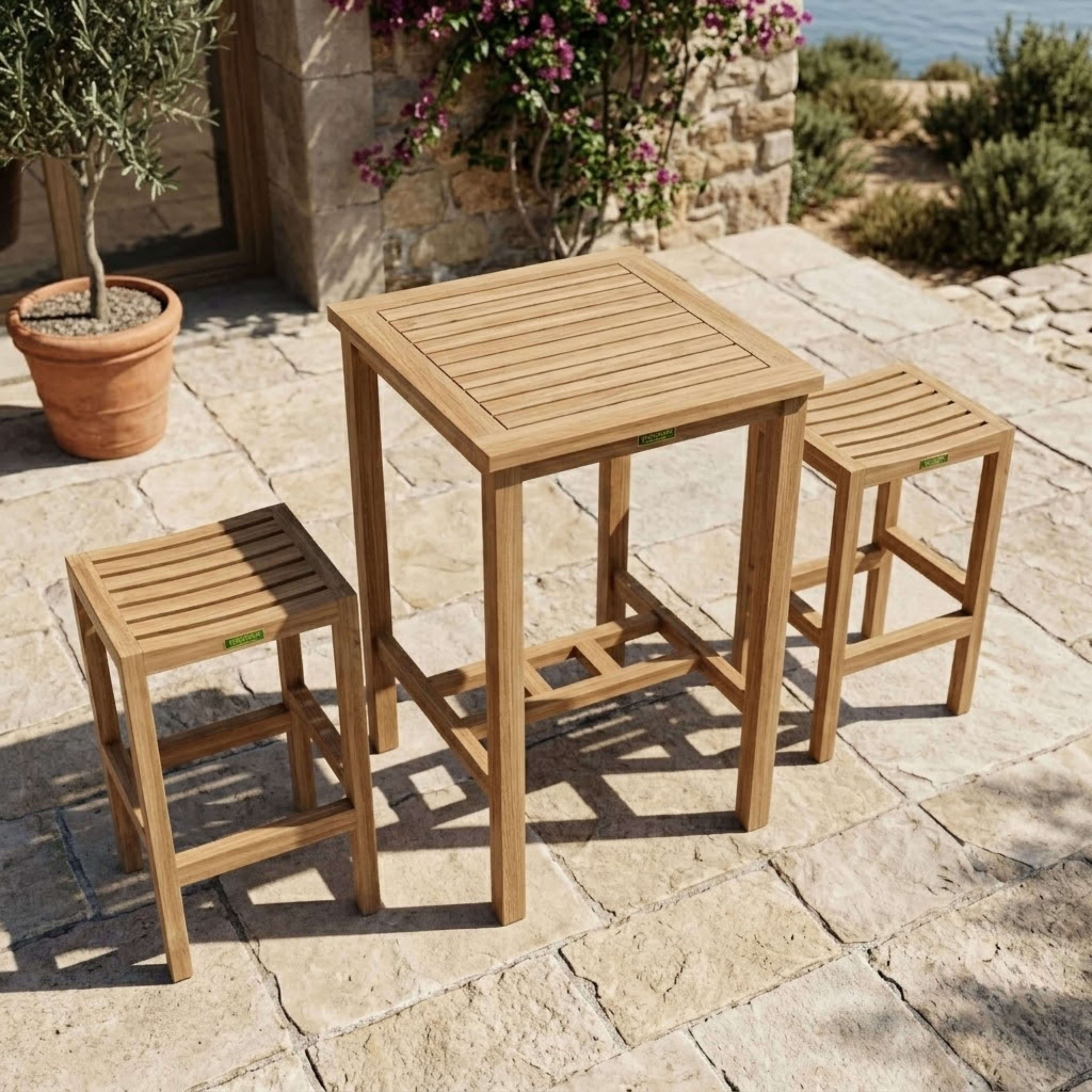 Avalon teak bar-height table with two backless chairs on a stone patio