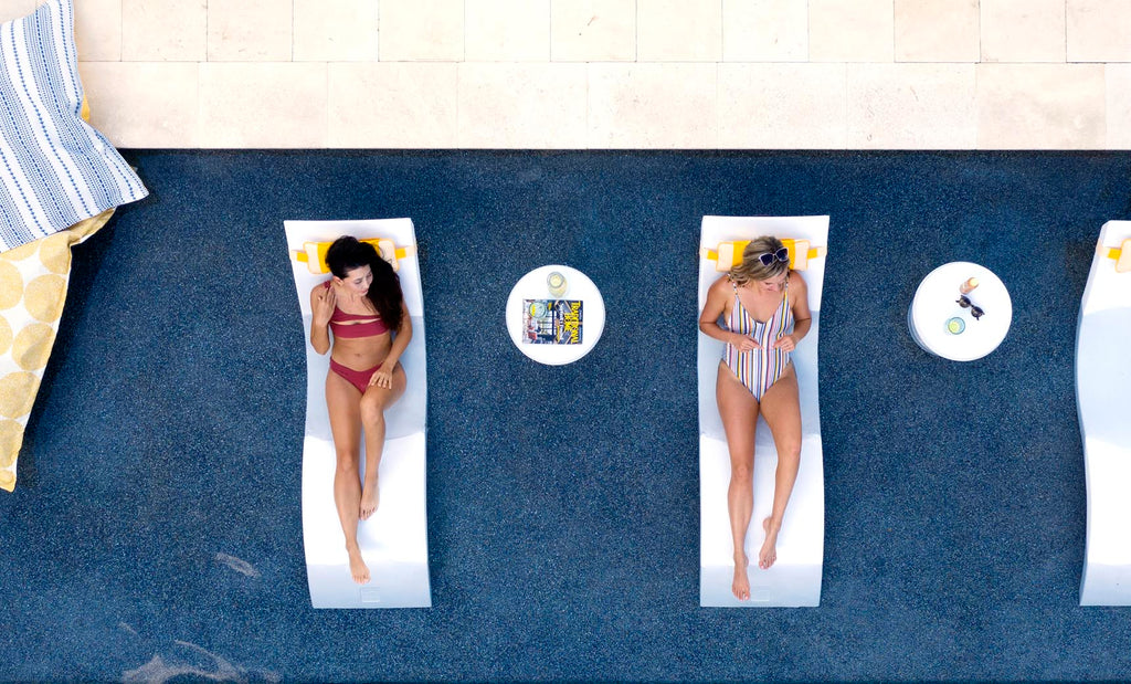 Overhead view of two people on White Signature Chaises with side tables on a sun shelf