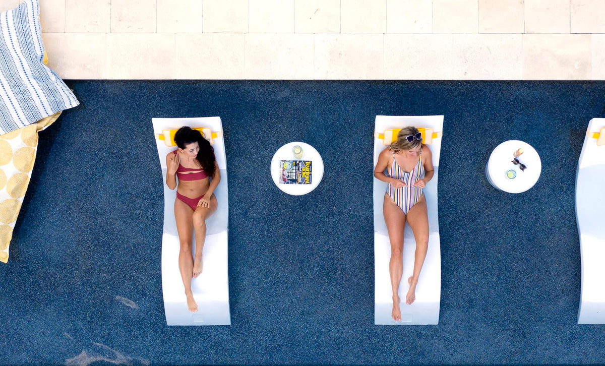 Overhead view of two people on White Signature Chaises with side tables on a sun shelf