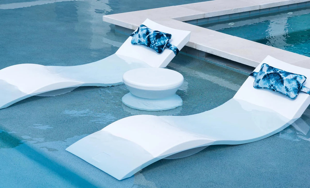 White solid-top Signature Side Table between two pool chaises with blue pillows; seating and pillows sold separately